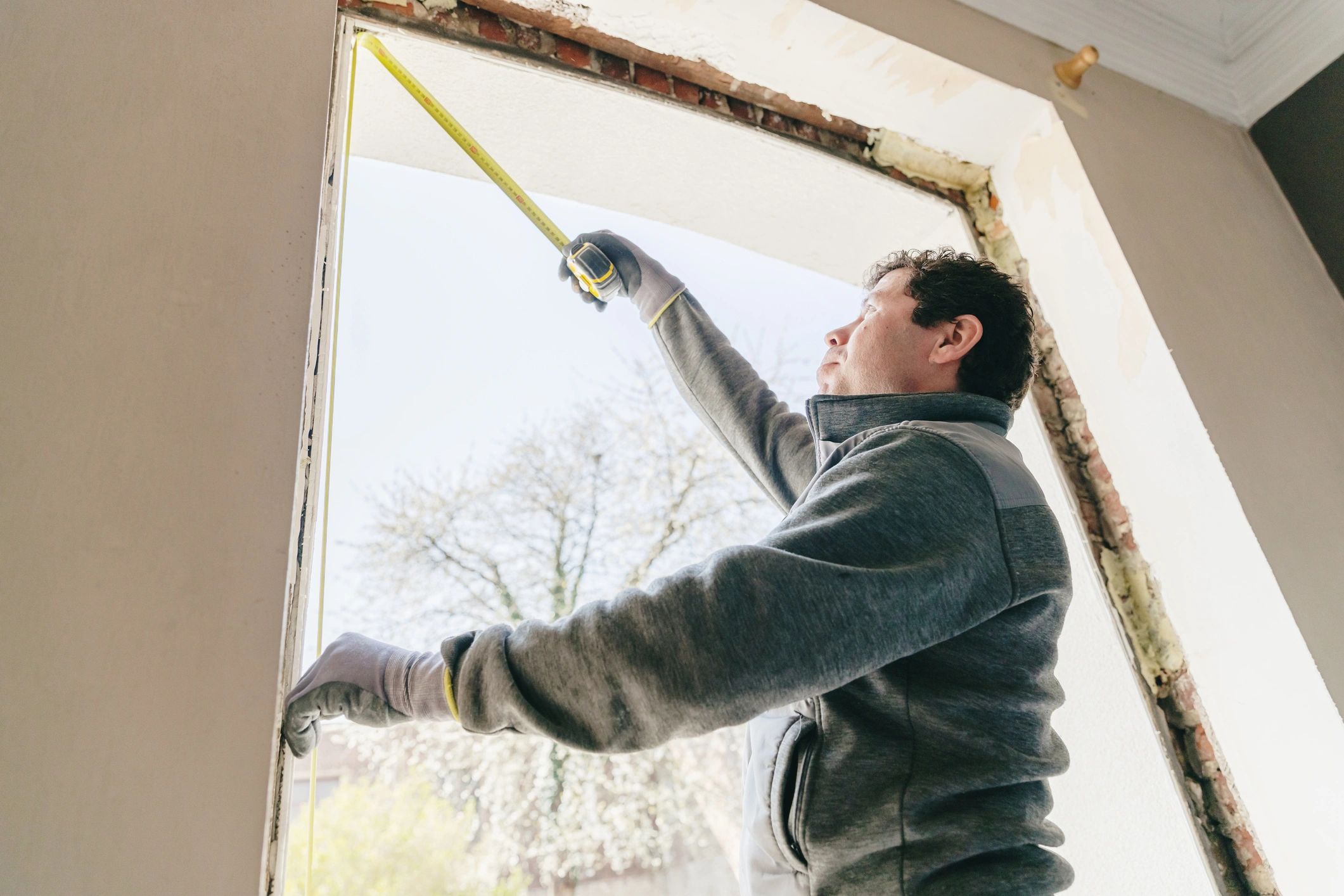 Technician measuring a window opening before installation